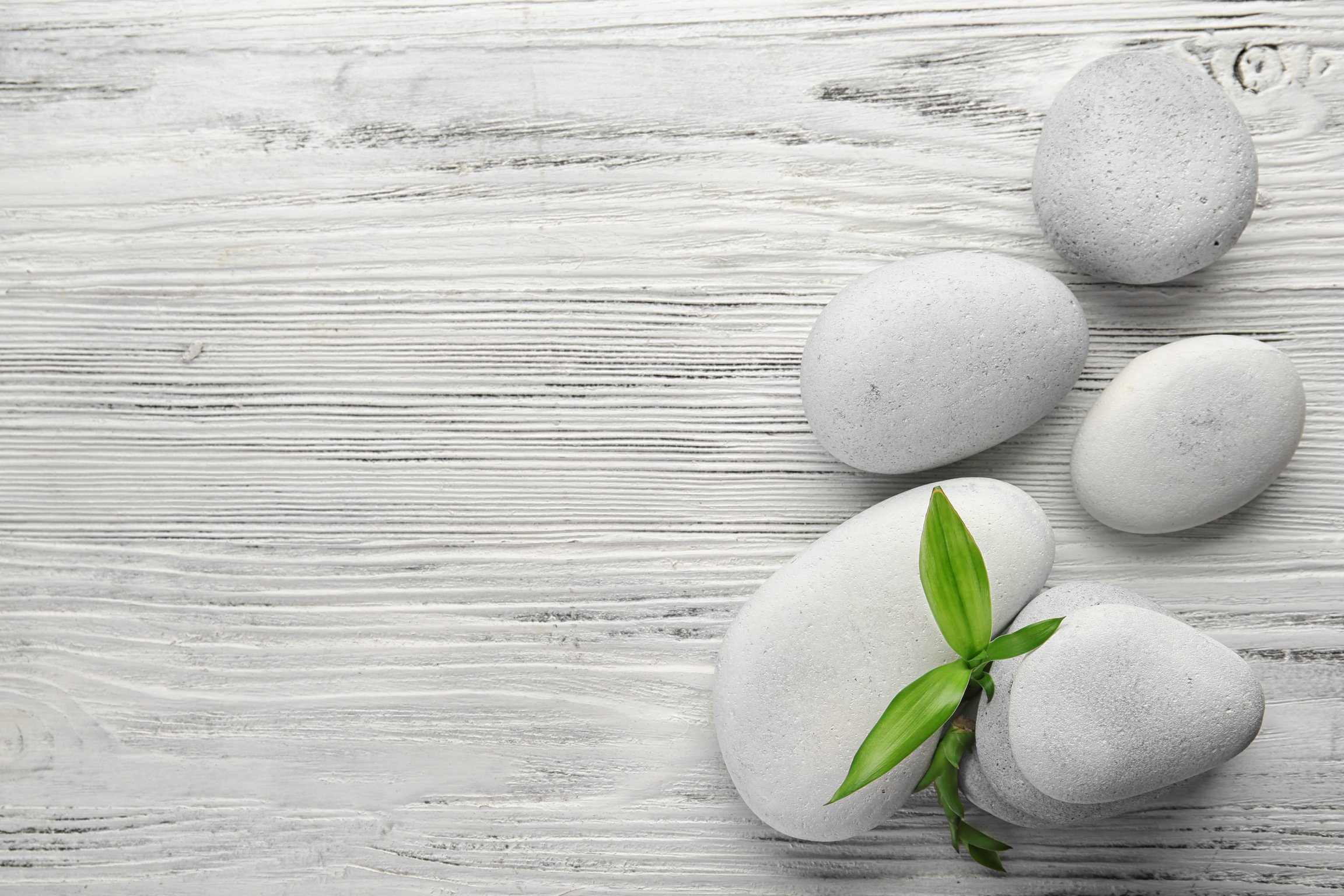 Hot Stones and Bamboo Leaves on Wooden Background 